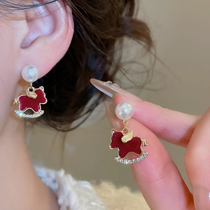 Detail shot of red enamel rocking horse earrings with pearls and crystals on model