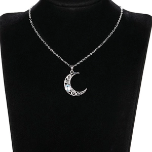 Detailed close-up of a silver crescent moon necklace with moonstone on black display