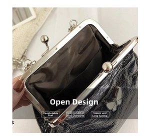 Detail of black pleated leather crossbody bag with silver butterfly clasp and metal chain