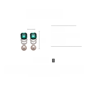 Detail view of emerald square stone and faux pearl earrings with interlocking C design