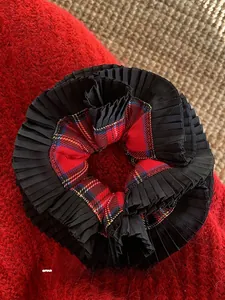 Detail of red and black plaid scrunchie with pleated trim on soft knit background