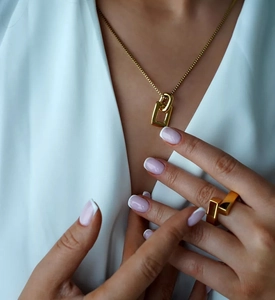 Detail of elegant gold interlocking square pendant necklace and matching open ring on model