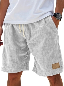 Detail view of men's linen shorts showing drawstring waist and brown leather patch accent