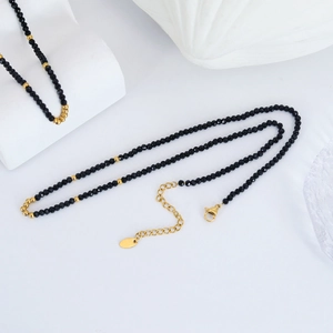 Faceted black beads and gold ball necklace with extension chain on white background