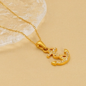 Gold plated anchor pendant necklace with white cubic zirconia pavé on beige texture