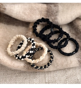 Flat lay of soft fabric hair ties in black, beige, and checkerboard pattern on a scarf