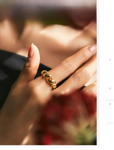 Detailed view of a gold braided croissant ring in sterling silver worn on a finger
