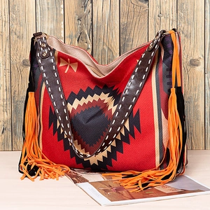 Detail of red woven bohemian tote with ethnic patterns, leather straps and fringe accents