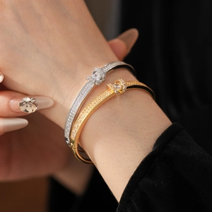Detail of gold and silver plated bangles with pavé diamonds and knot design