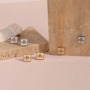Detail of square bee pendant necklace and earrings set on a natural stone surface