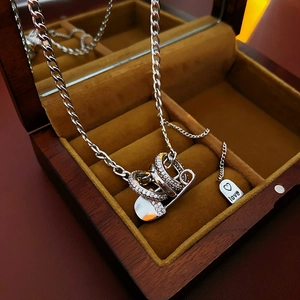 Detailed view of silver paperclip pendant necklace with zircon and love charm