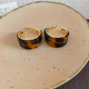 Détail de créoles plaquées or 18 carats avec résine marron à texture écaille
