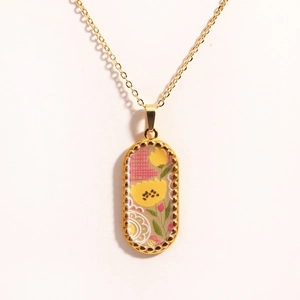 Macro view of oval gold-plated necklace pendant with fabric floral embroidery detail