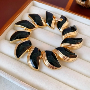 Détail du bracelet feuille dorée vintage avec incrustations noires sur velours blanc
