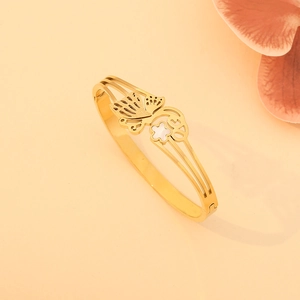 Gros plan du bracelet en acier doré avec papillon ajouré et détail de fleur en nacre