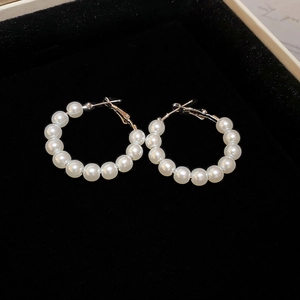 Detailed close-up of beaded white pearl hoop earrings resting on black velvet fabric