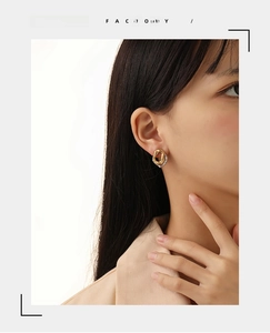 Macro view of irregular lava texture earrings in mixed gold and silver on a model
