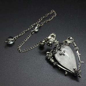 Detailed view of silver skull pendulum pendant with clear crystal and ornate engravings