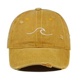 Close-up of ginger yellow washed cotton baseball cap with white wave embroidery and distressed details