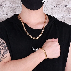 Close-up of golden Cuban link chain necklace and bracelet set on a street style model