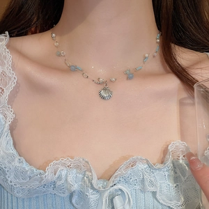 Detail of beaded pearl necklace with silver shell pendant on a female model neck