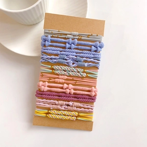 Detailed view of ten colorful elastic hair ties with gold beads on a brown card