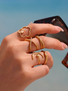 Close-up of stacked gold-plated rings with zircon inlays and floral geometric designs