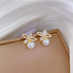 Detailed macro view of gold plated bow pearl earrings with sparkling zircon inlay