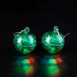 Close-up of green disco ball earrings with colorful light reflections on black background