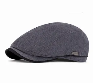 Detail of dark gray herringbone newsboy cap featuring a branded metallic side emblem