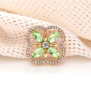 Macro shot of green marquise clover charm with crystals on gold plated metal base