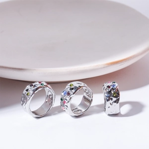 Macro shot of silver lava textured rings with colorful zircon gemstones on a white surface