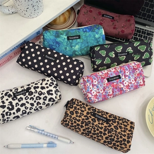 Flat lay of vintage floral and leopard print canvas pencil cases on a desk setup