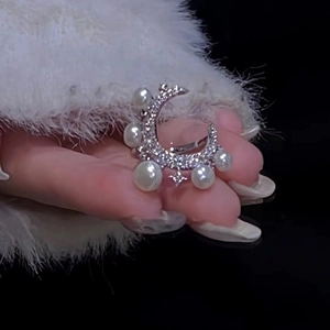 Elegant silver star and moon ring with pearls and cubic zirconia on a plush background