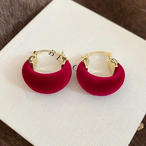 Close-up of red velvet hoop earrings with gold clasp on white gift box packaging