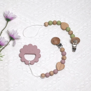 Detail of lion-shaped silicone teether with wooden bead pacifier clip on white blanket