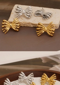 Detail view of bow-shaped stainless steel earrings in gold and silver finishes