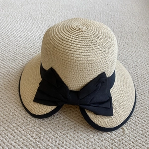 Detalle del sombrero de paja beige con lazo negro grande y textura de paja tejida
