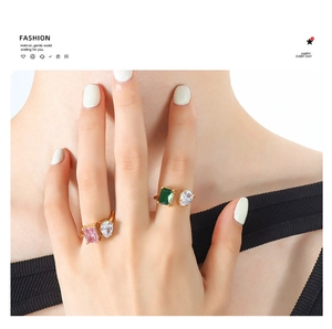Detail of gold-plated open rings featuring emerald green and pink teardrop zircon stones