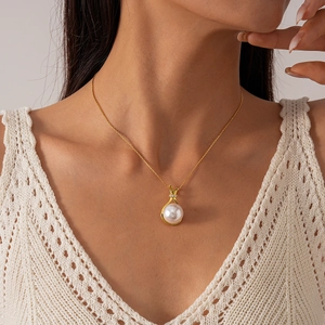 Close-up of golden necklace with a lustrous white pearl pendant and zircon details