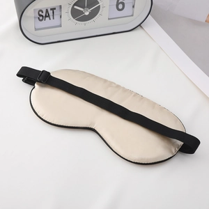 Champagne silk sleep mask with adjustable black strap and flip clock decor on white desk