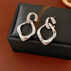 Dettaglio macro di orecchini a cerchio intrecciati in argento con zirconi in cofanetto nero