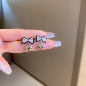 Macro detail of bow-shaped stud earrings with black and white pavé cubic zirconia