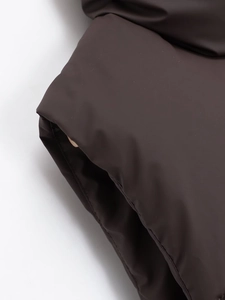 Detail of dark brown padded vest showing soft matte texture and premium stitching