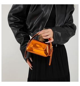 Detailed macro shot of bright orange patent leather mini bag with shiny metallic finish