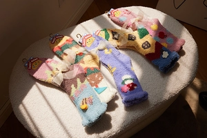 Close-up of four pairs of plush coral fleece socks with cute 3D cartoon decorations