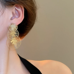 Gros plan détaillé de boucles d'oreilles pendantes dorées à disques évidés superposés