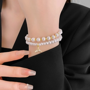 Detail of double-layer pearl bracelet with gold-plated fishtail pendant on model wrist