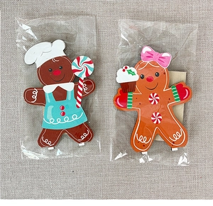 Detailed view of two wooden gingerbread man ornaments with lollipop and cupcake accessories