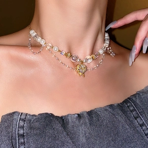 Detail of layered necklace with pearls, crystal beads and a gold heart pendant on model
